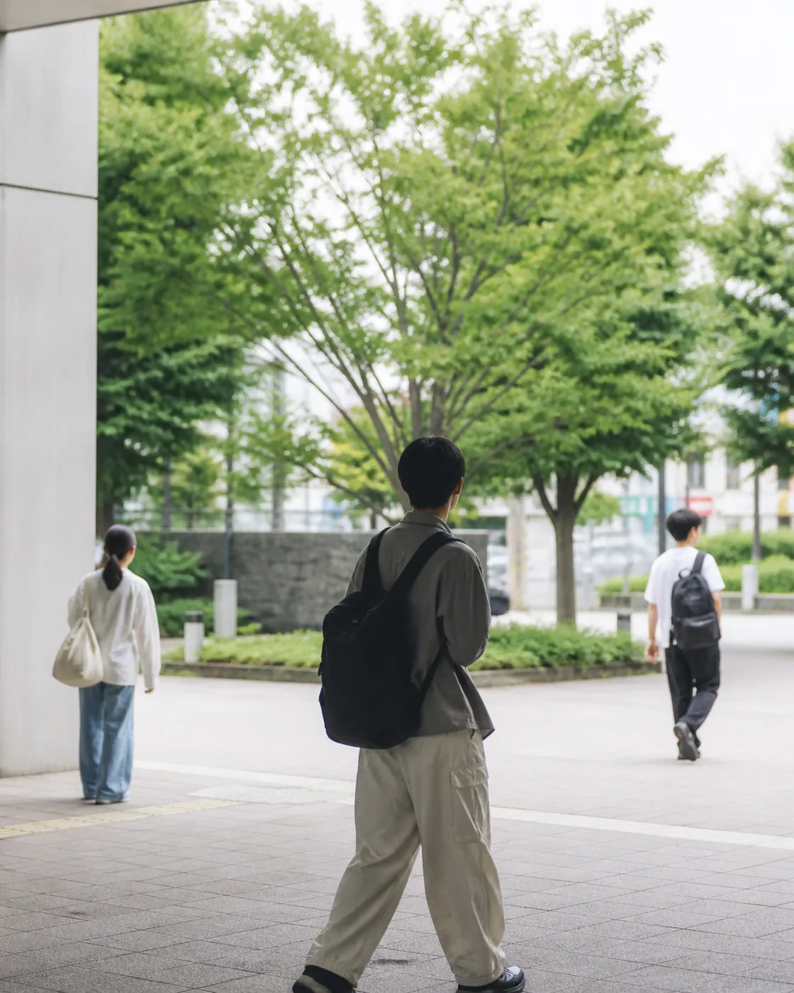 緑のある待ち合わせ場所へ別々に向かう3人